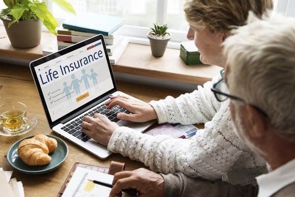 an elder couple searching for life insurance on a laptop